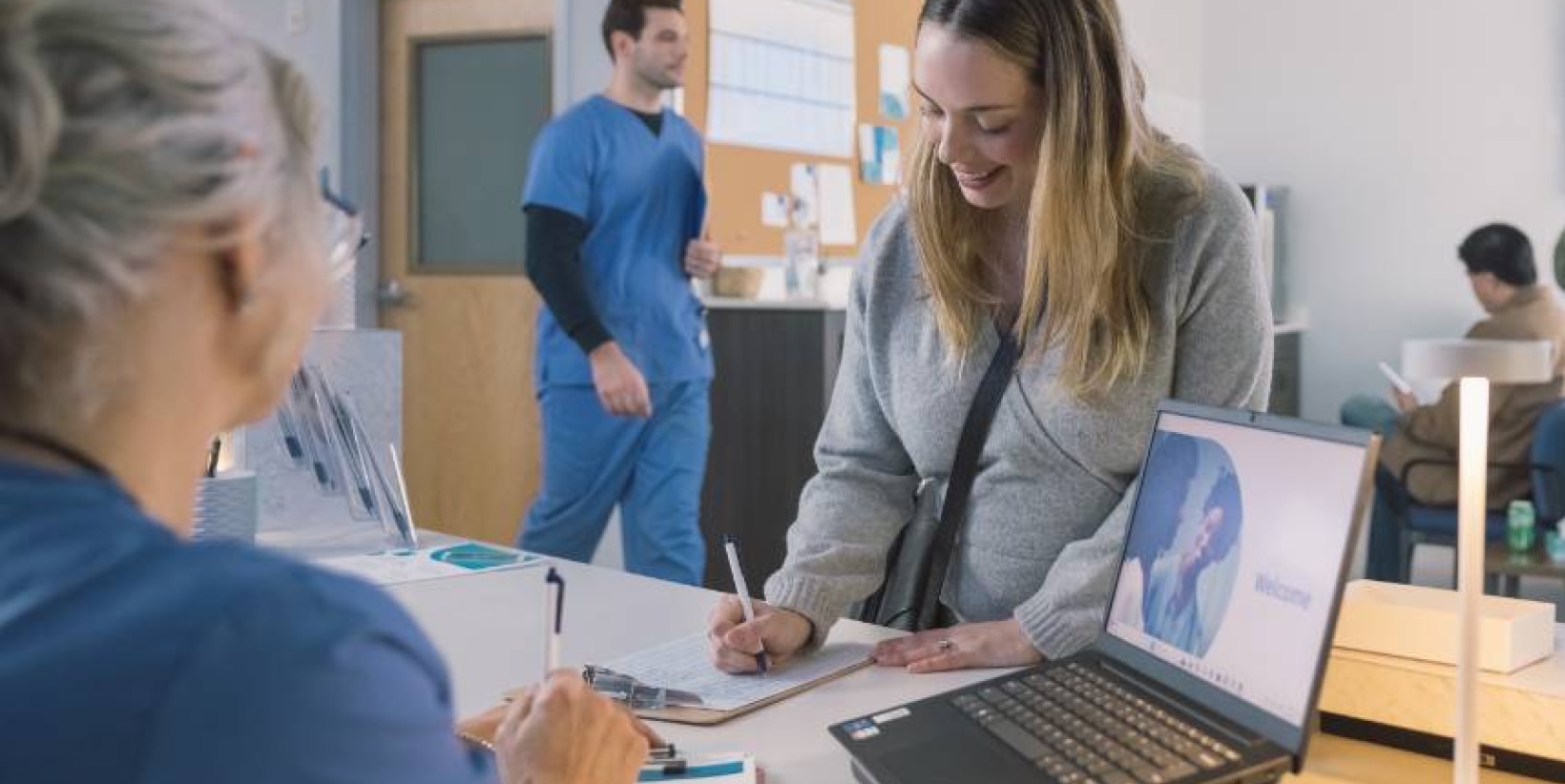 Pictured, a woman at a healthcare facility filling out a form.